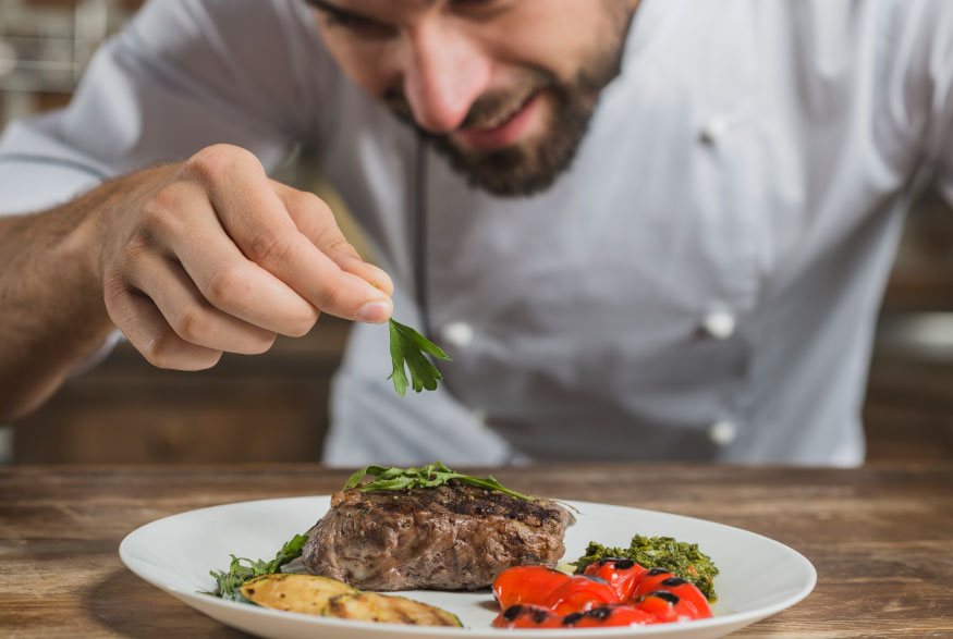 male-chef-garnishing-prepared-dish-kitchen-counter